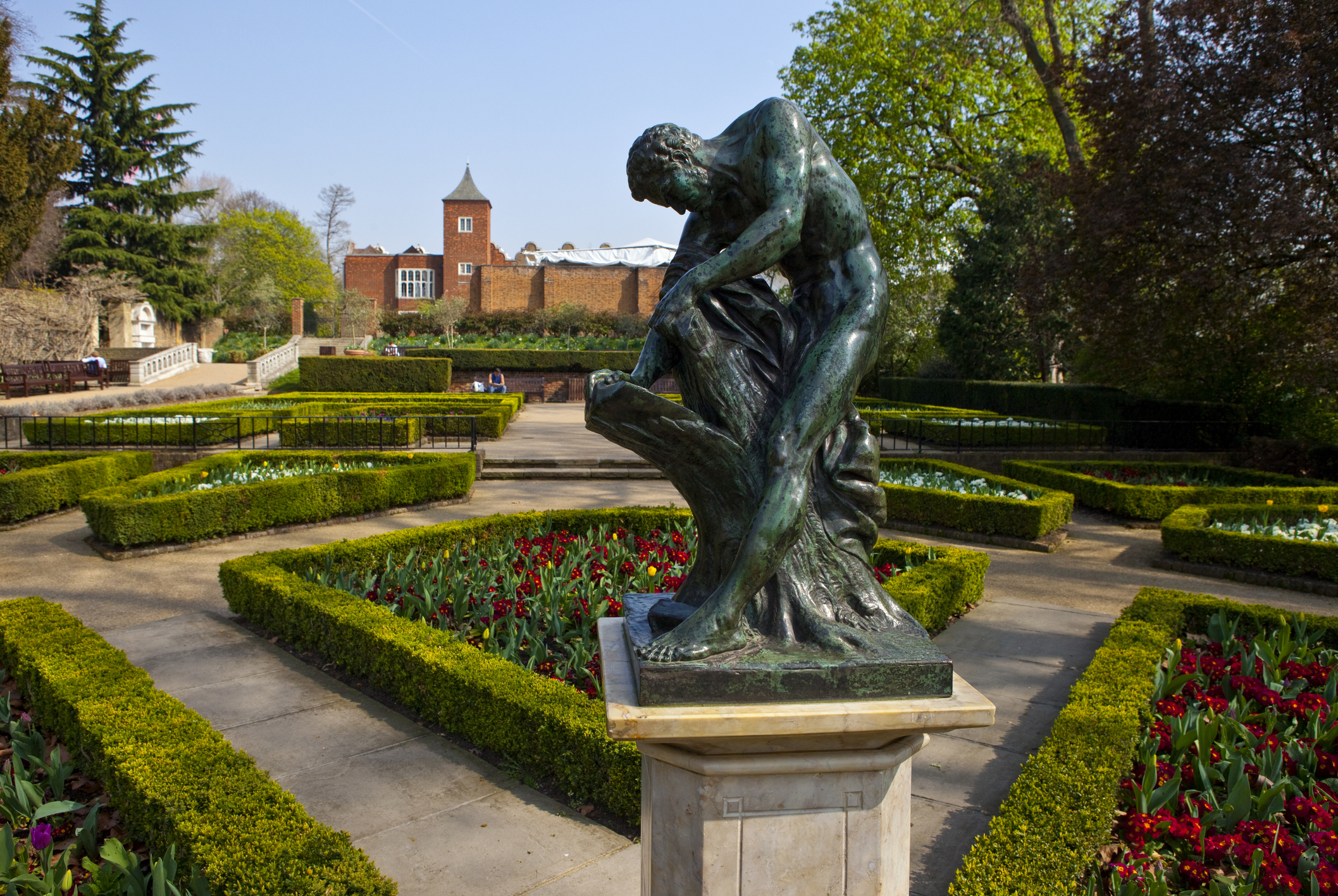 Holland Park in London featuring flowers, shrubs and a statue. Photograph by Chris Dorney